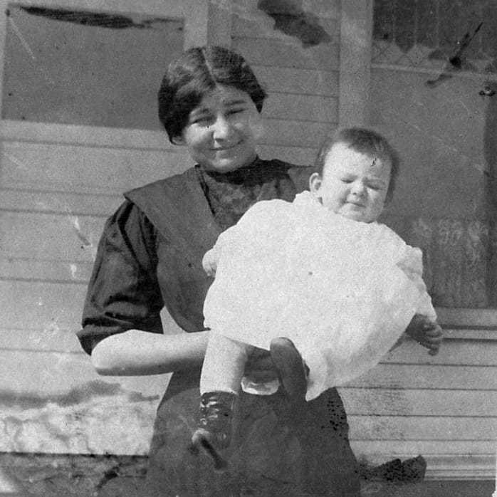 A black and white photograph of Elizabeth as a ***** infant in white garbs being held by her Sioux nanny.