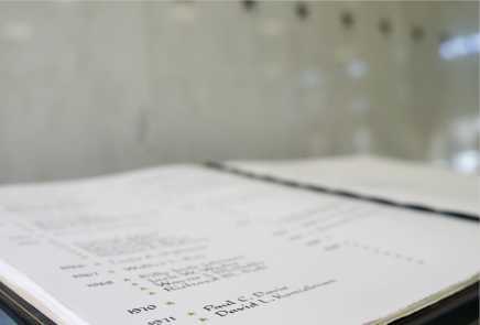 A white book with dark lettering listing the names of fallen CIA officers alongside gold stars.