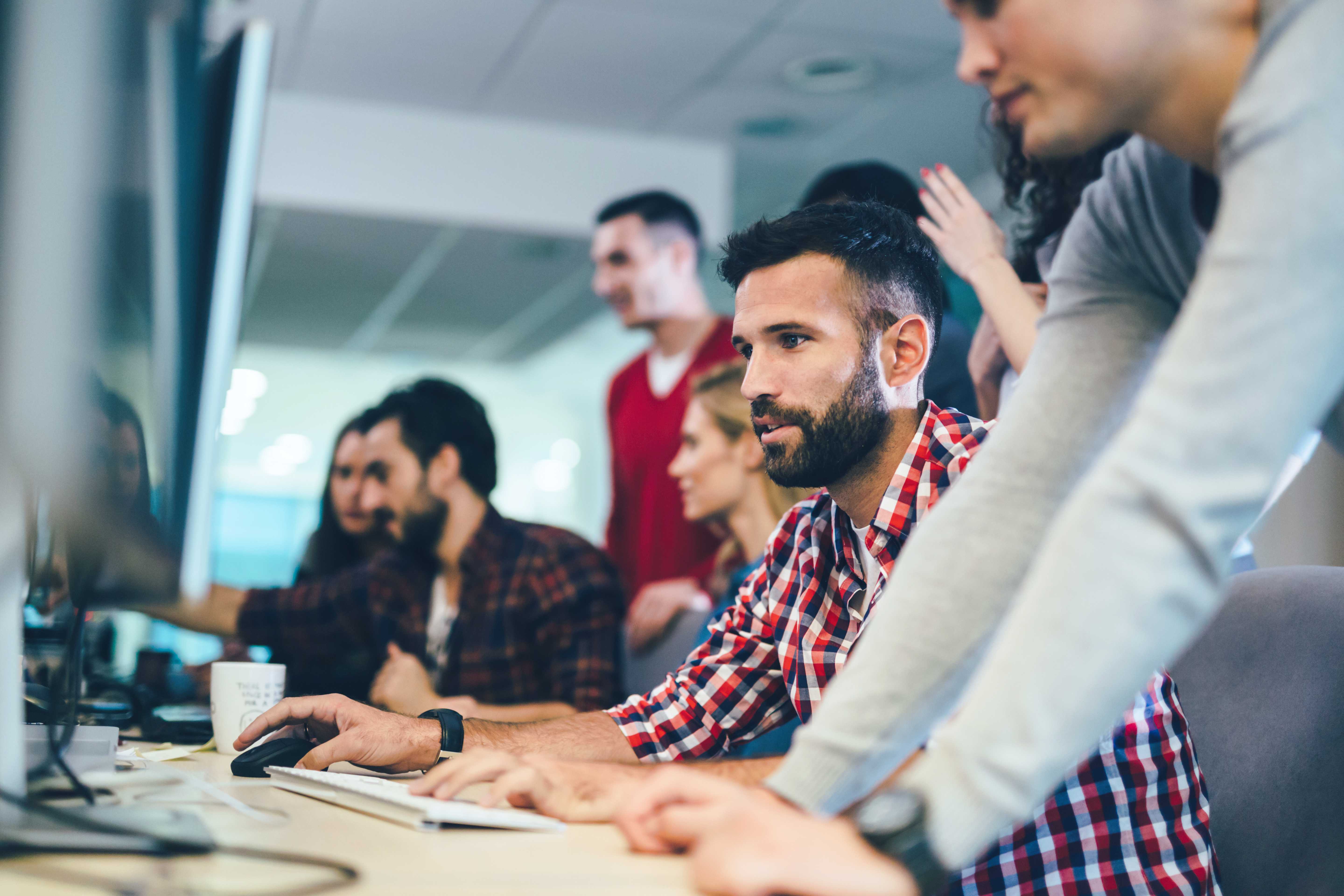 A group of ***** professionals in business casual clothes working on several computers.